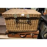 A vintage tan suitcase together with woven wicker hamper