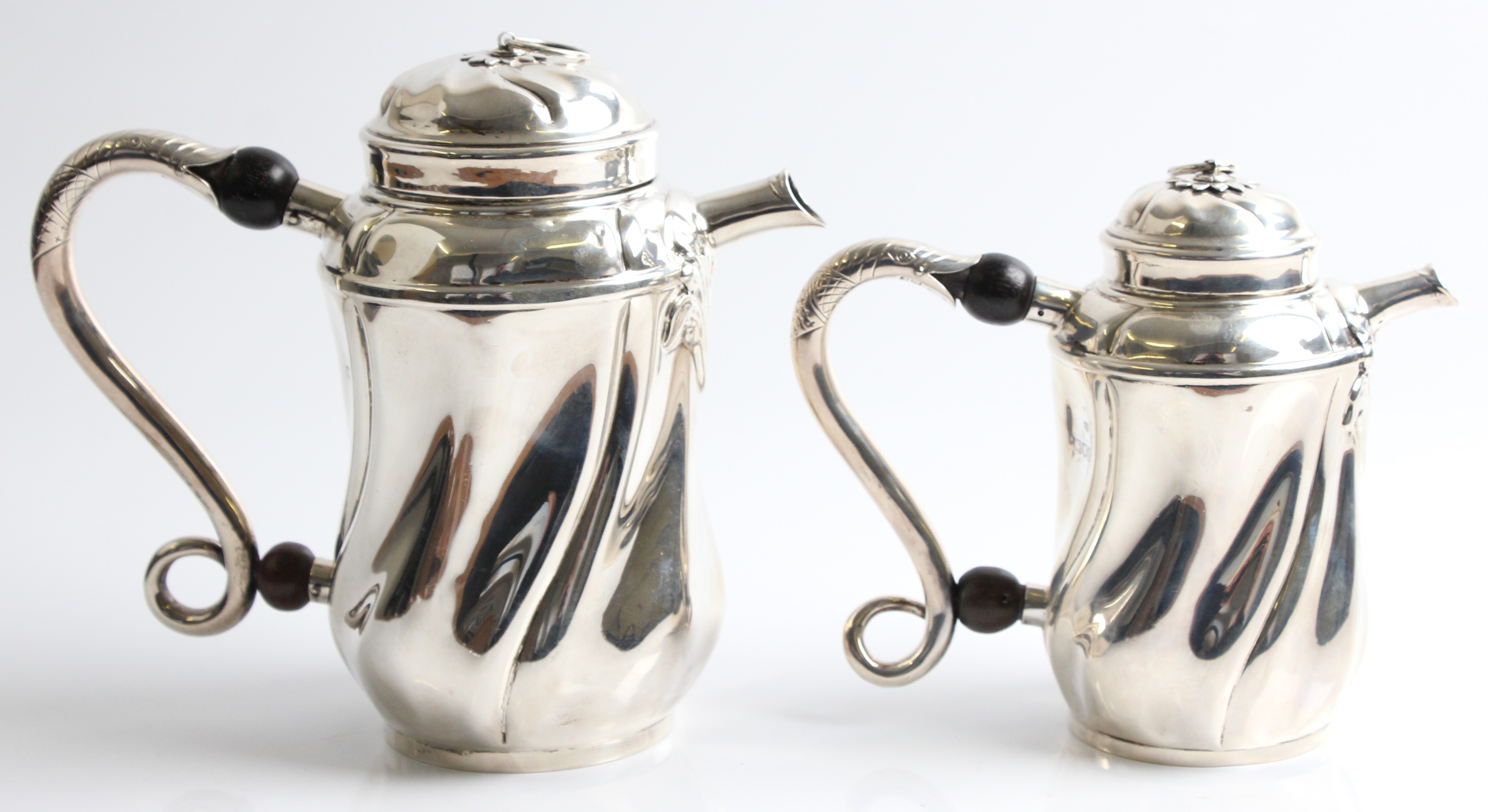 A Goldsmiths & Silversmiths Company silver coffee pot and tea pot, both of swirled design, with fish