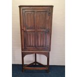 A late 18th century style linen fold front corner cupboard on stand
