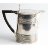 A white metal tankard converted into jug, with repeat linear design to body and lid, with wooden