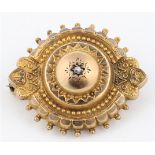 A diamond brooch, the circular Etruscan design set centrally with a rose cut diamond accent,
