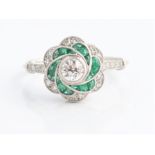 An emerald and diamond flower design dress ring, set with a central round brilliant cut diamond,