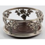 A grape design wine coaster, the open metalwork body featuring repousse vine with grapes design,