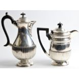 A silver coffee pot and teapot, both having gadrooned lower bodies, one having foliage design