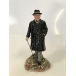 A Royal Doulton figure showing Sir Winston Churchill in a black trench coat and a walking stick in