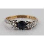 A sapphire and diamond three stone ring, set with a central round cut sapphire flanked to either