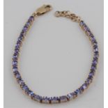 A tanzanite tennis bracelet, set with 32 oval cut tanzanites, stamped 375, length approx. 17cms.