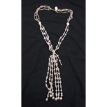 A triple strand string of cultured pearls in gathered design, comprising white, peach and