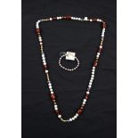 A string of cultured pearls, comprising white, brown and golden pearls, spaced by red hardstone