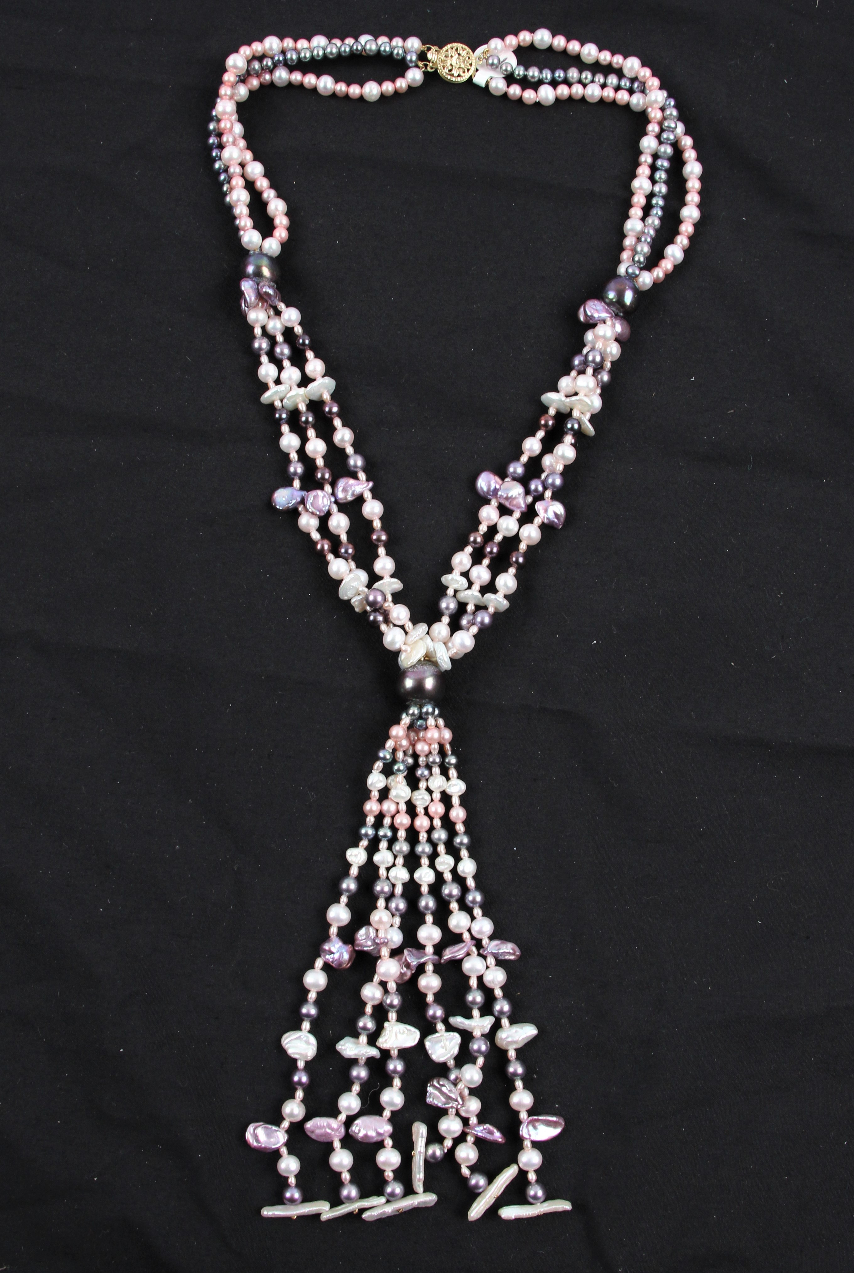 A triple strand string of cultured pearls in gathered design, comprising pink, purple white and