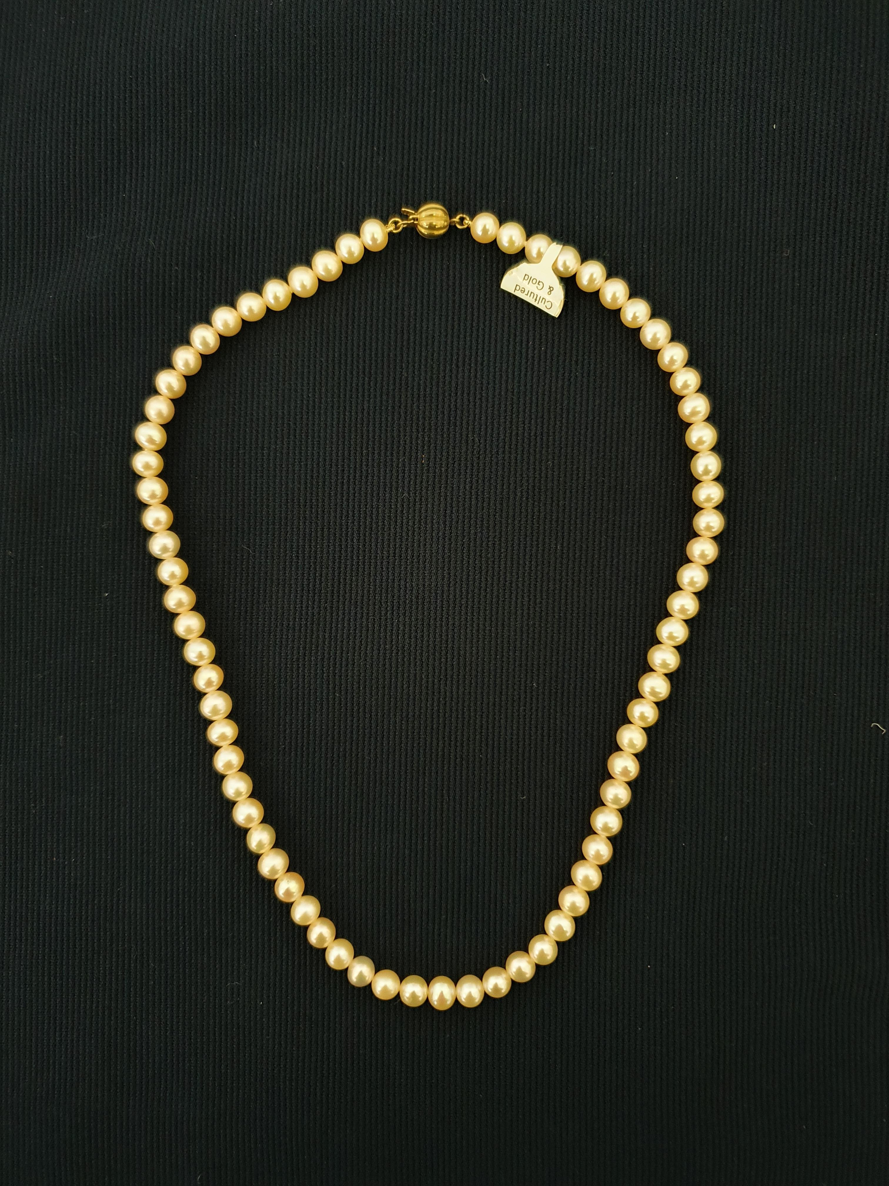 A string of peach cultured pearls, clasp stamped 375, length approx. 16". IMPORTANT: Bidding via