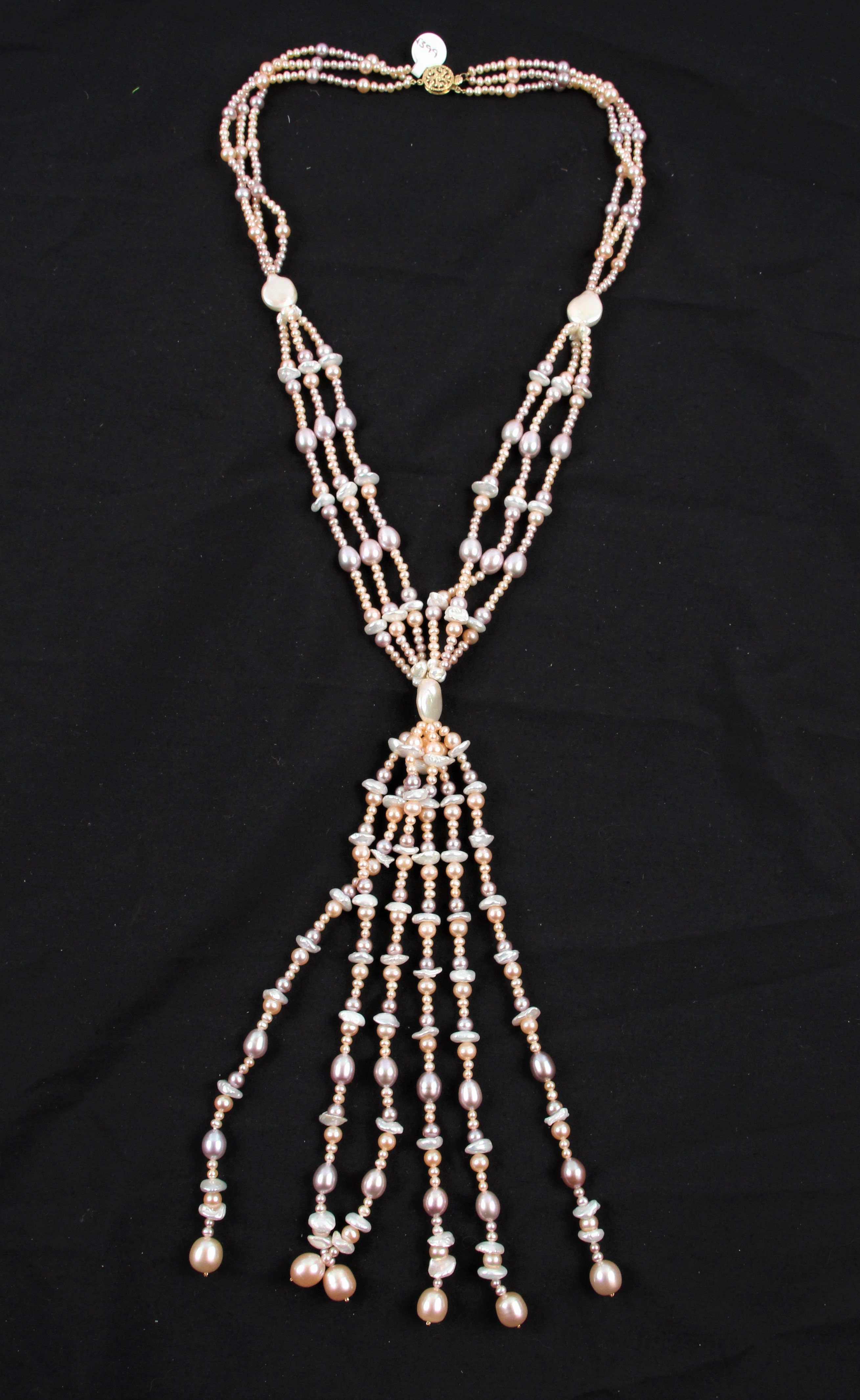 A triple strand string of cultured pearls in gathered design, comprising white, peach and