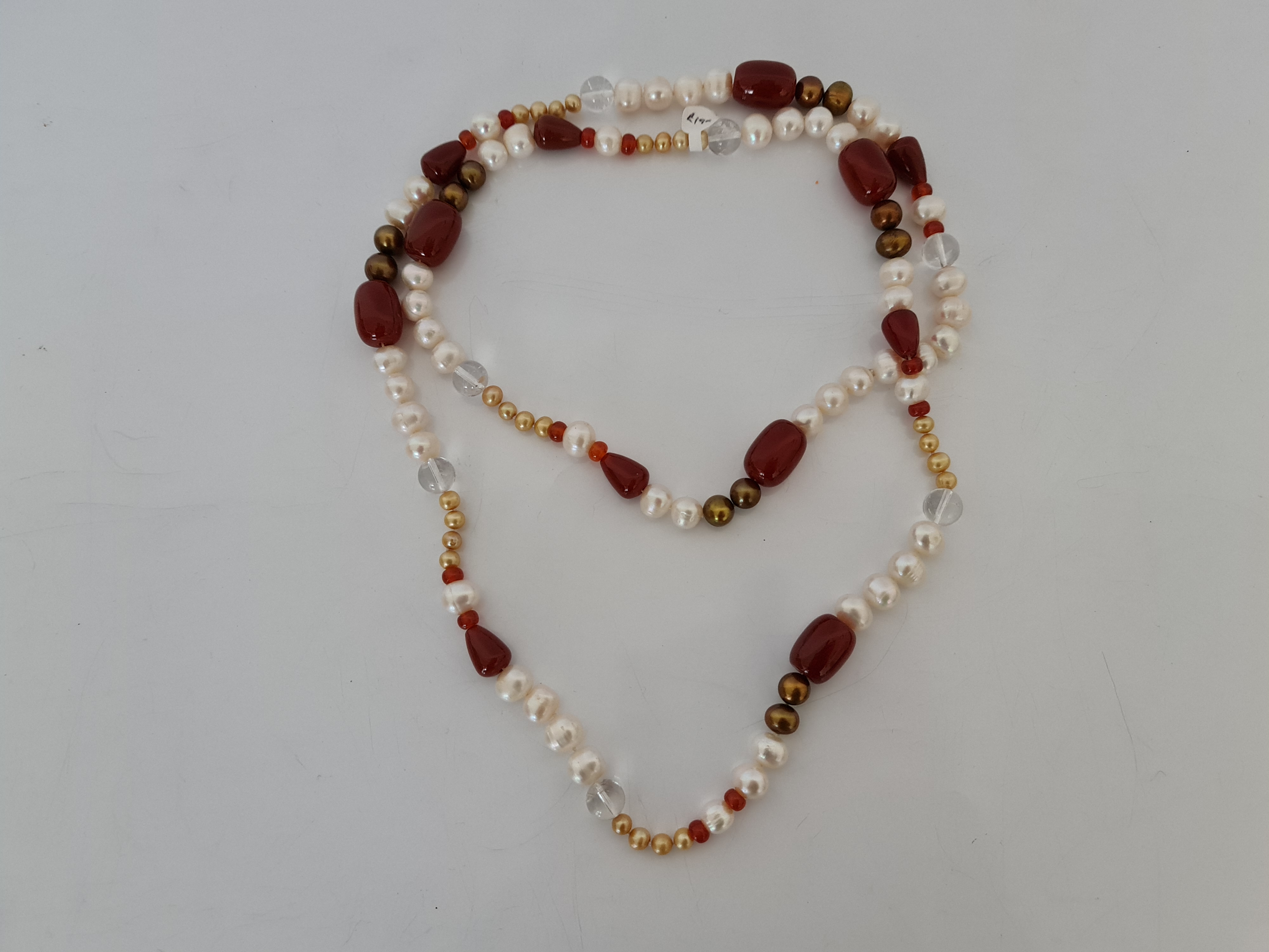 A string of cultured pearls, comprising white, brown and golden pearls, spaced by red hardstone