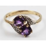 A hallmarked 9ct yellow gold amethyst and diamond ring, set with two round cut amethysts flanked