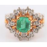An emerald and diamond dress ring, set with a central cushion cut emerald, measuring approx.