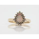 A hallmarked 9ct yellow gold opal and diamond cluster ring, set with a pear cut opal cabochon,