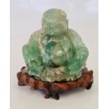 A large Chinese green hardstone figure of a Buddha on carved wooden base.
