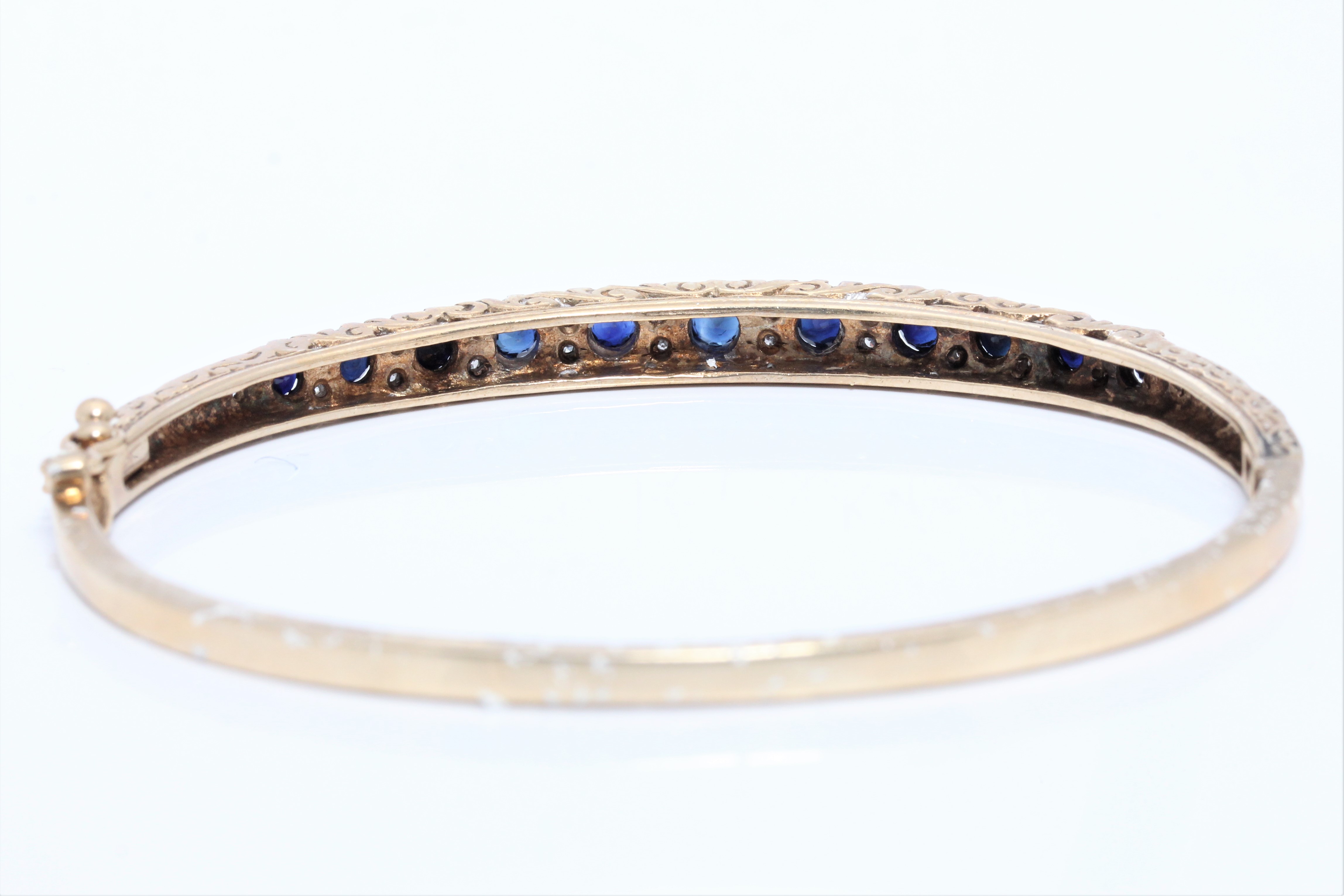 A hallmarked 9ct yellow gold sapphire and diamond hinged bangle, set with eleven graduated round cut - Image 3 of 3