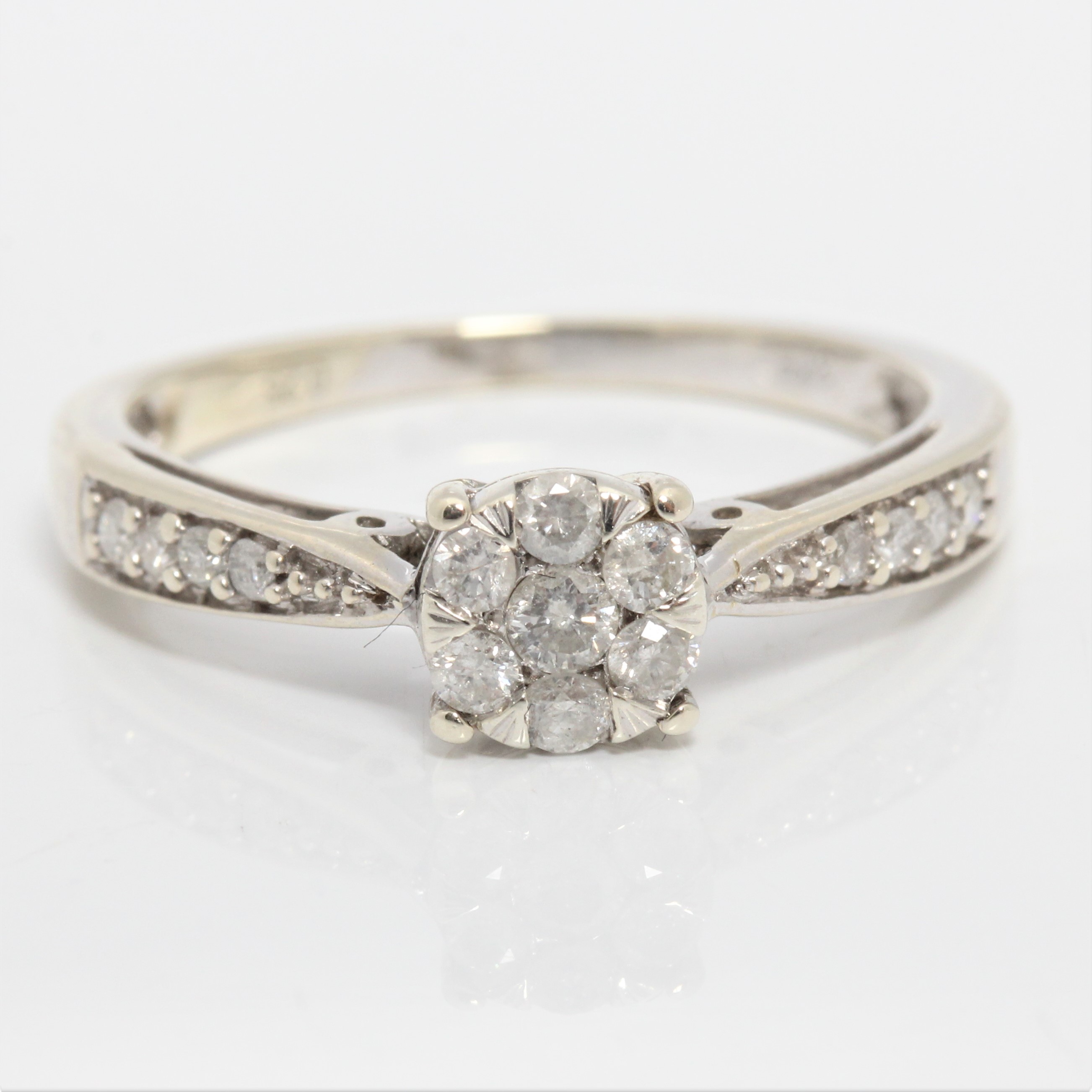 A diamond cluster ring, set with seven round brilliant cut diamonds in flower cluster, with