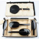 A matched Art Deco silver and black enamel dressing table set, comprising a mirror, two hair brushes