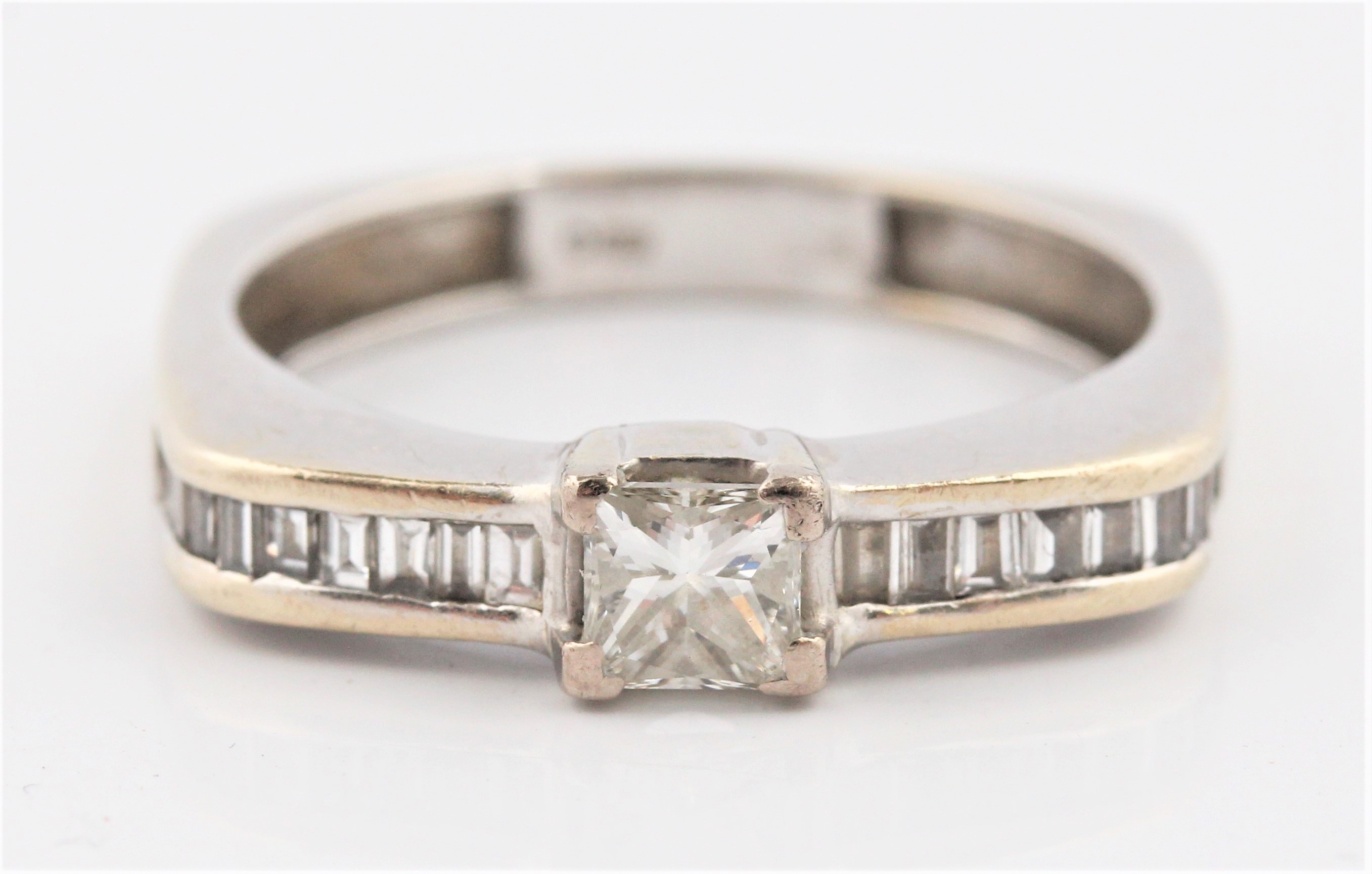A hallmarked 18ct white gold diamond ring, set with a principal princess cut diamond measuring