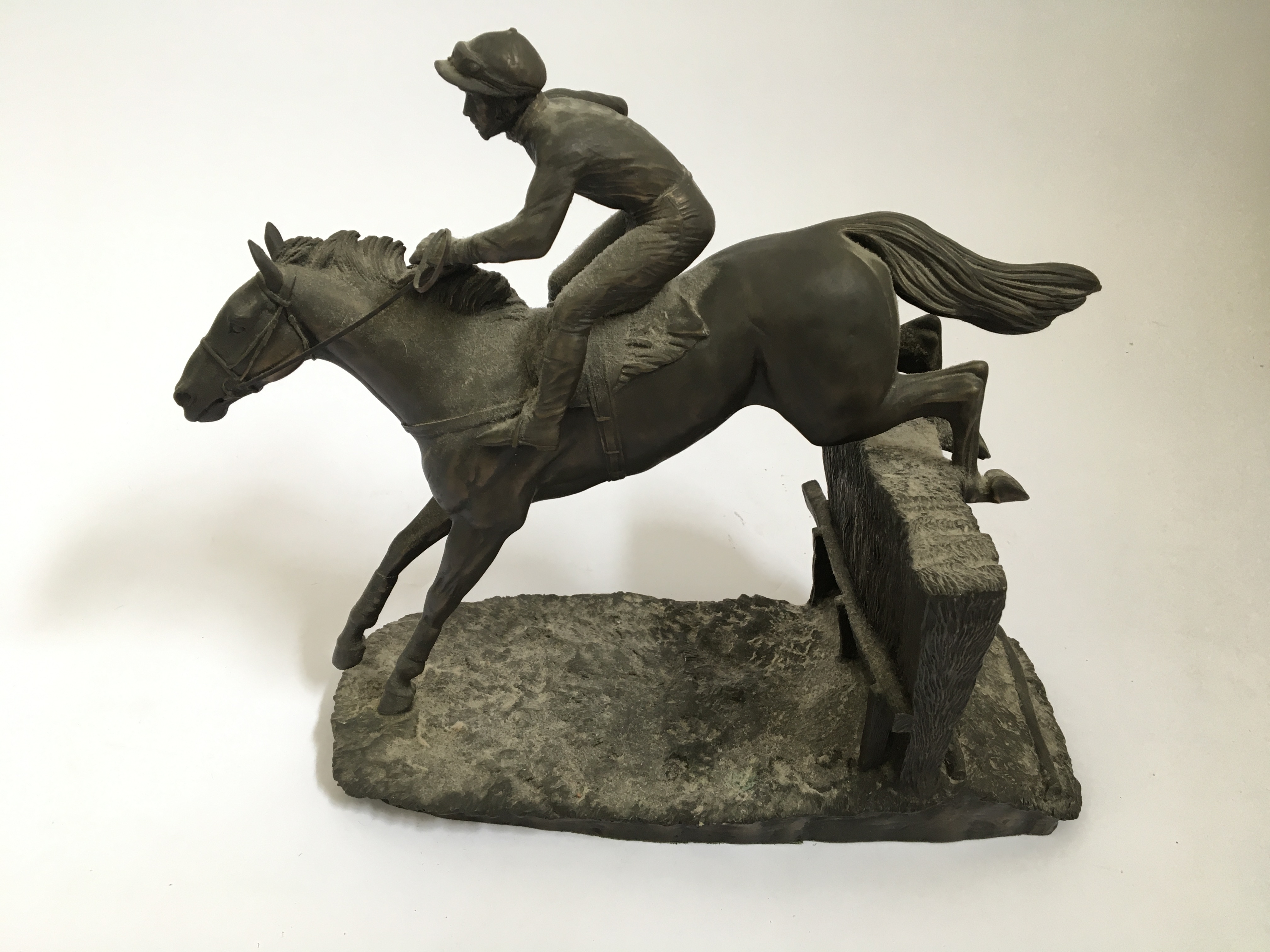 A bronze finished resin figure, titled ‘Over the Last’, jockey and horse