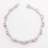 A pink topaz and diamond set bracelet, set with twelve oval cut pink topaz, separated by diamond