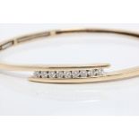 A diamond set bangle, the cross over design set with nine round brilliant cut diamonds, total