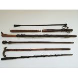 A collection of walking canes of various designs, together with two truncheons and a riding crop. No