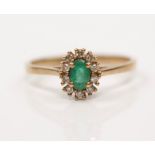 A 9ct yellow gold emerald and diamond cluster ring, set with an oval cut emerald surrounded by a