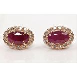 A pair of treated ruby and diamond cluster earrings, each set with an oval cut glass-filled ruby,
