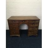 A six drawer and one cupboard mahogany desk.