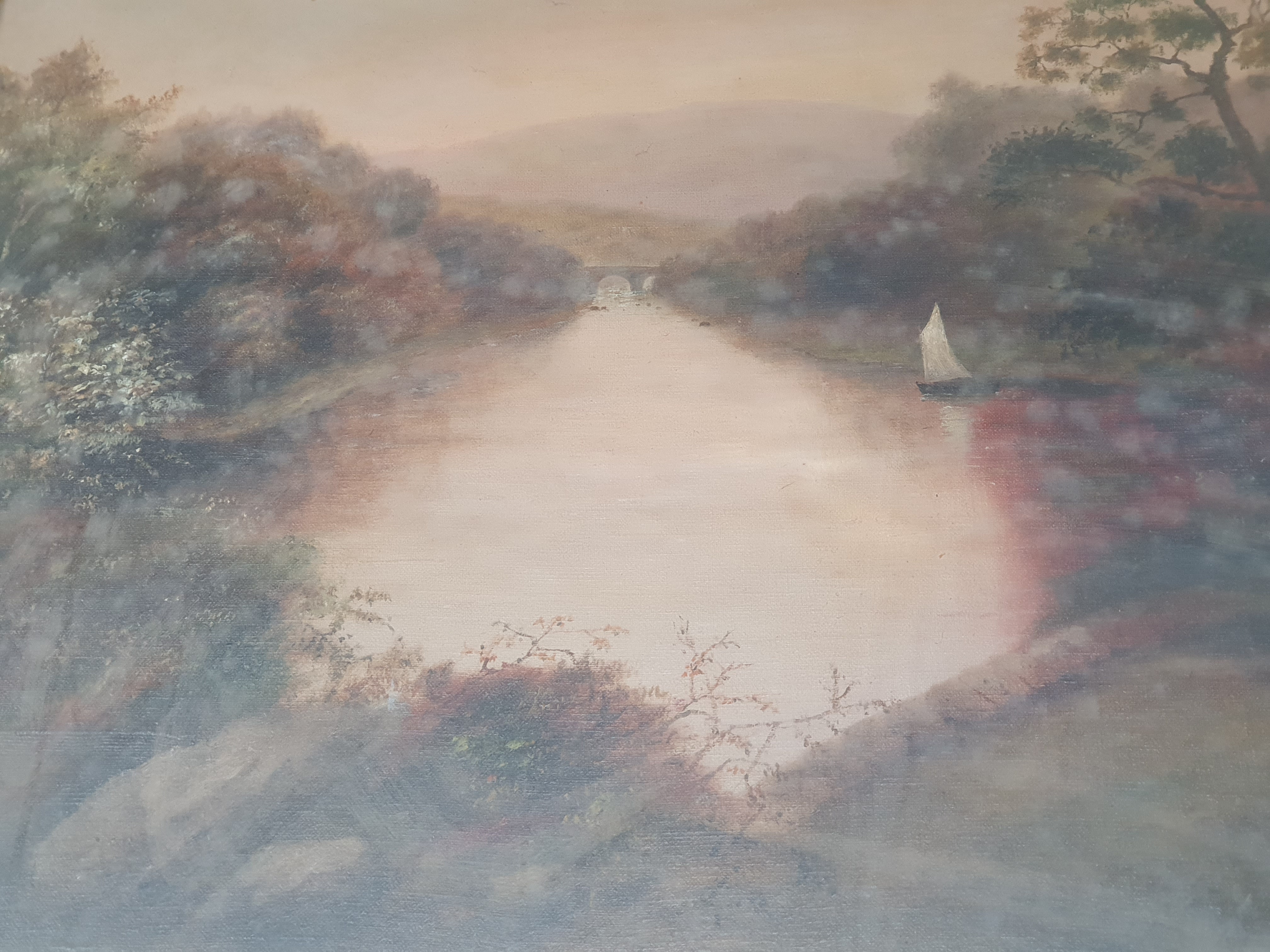 An oil on canvas landscape painting of a river with a sail boat and bridge in distance. Approx. 49.