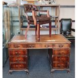 A mahogany reproduction desk together with a brown leather tub chair.