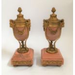 A pair of pink marble and ormulu, rams head and rose swag decorated urns with reversible top