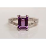 A hallmarked 9ct yellow gold amethyst and diamond ring, set with a central emerald-cut amethyst to