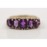 An amethyst and diamond ring, set with five graduated oval cut amethysts, set with rough cut diamond