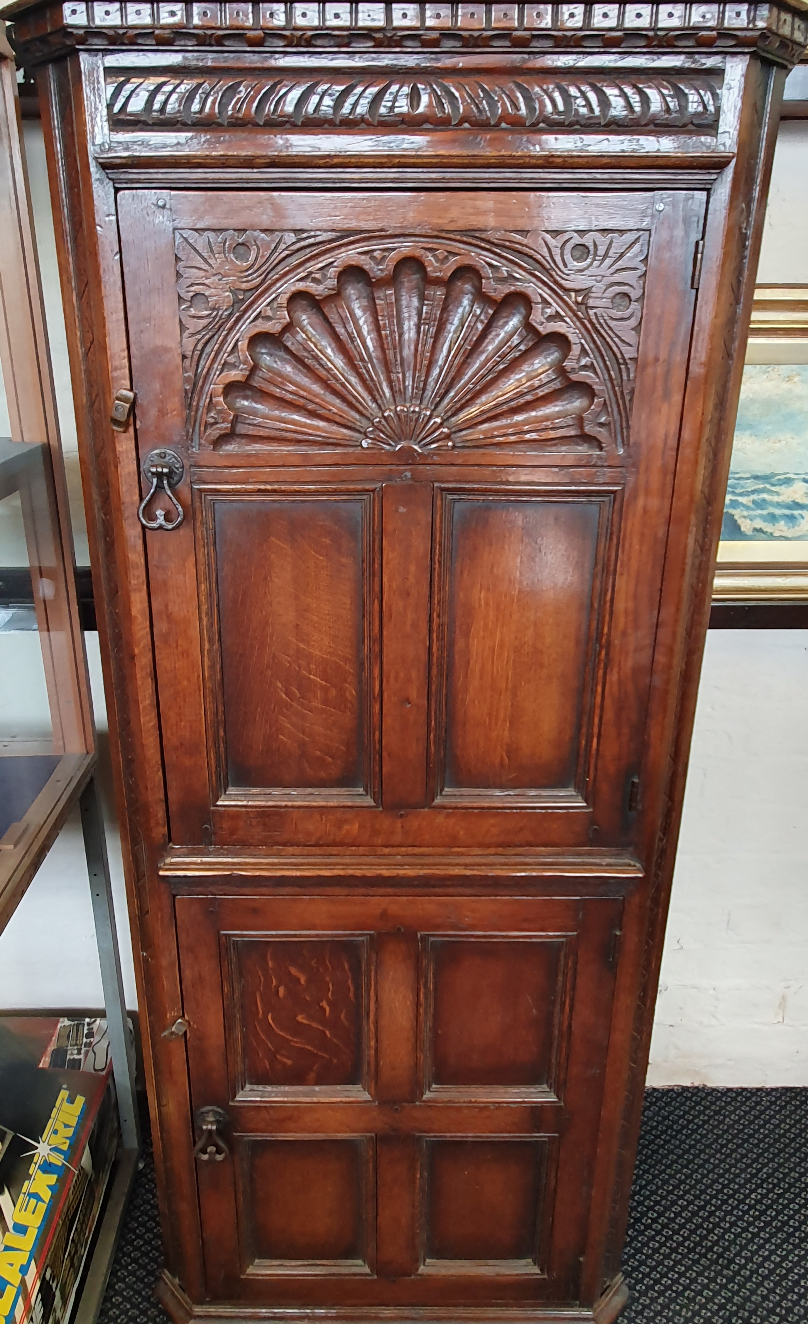 A distressed oak two-door corner cabinet carved panel to front,