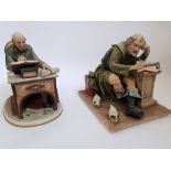 Two Capo Di' Monte figurines of aged writers at their work, with scattered and discarded paper at