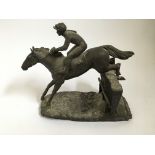 A bronze finished resin figure, titled ‘Over the Last’, jockey and horse