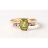 A hallmarked 9ct yellow gold peridot and diamond ring, set with a central emerald-cut peridot,