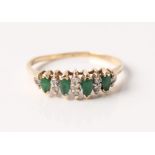 An emerald and diamond ring, set with four marquise cut emeralds, separated by round cut diamond