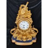 A French gilded bronze mantle clock with musical instruments to top floral swag design on base.