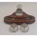 A walnut inkwell stand with glass bottle with two separate glass inkwells.