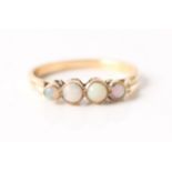 A four stone opal ring, set with four graduated round opal cabochons, unmarked yellow metal, ring