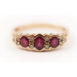 A hallmarked 9ct yellow gold ruby and diamond ring, set with three oval cut rubies separated by