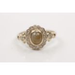 A yellow stone and diamond cluster ring, set with a central cats-eye yellow stone surrounded by a