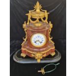 A French red marble mantle clock with gilded bronze urn to top on four leaf design feet.approx