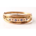 An late 19th/ early 20th Century hinged bangle, star set with four round blue pastes and three