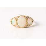 A hallmarked 18ct yellow gold opal and diamond ring, set with three oval opal cabochons spaced by